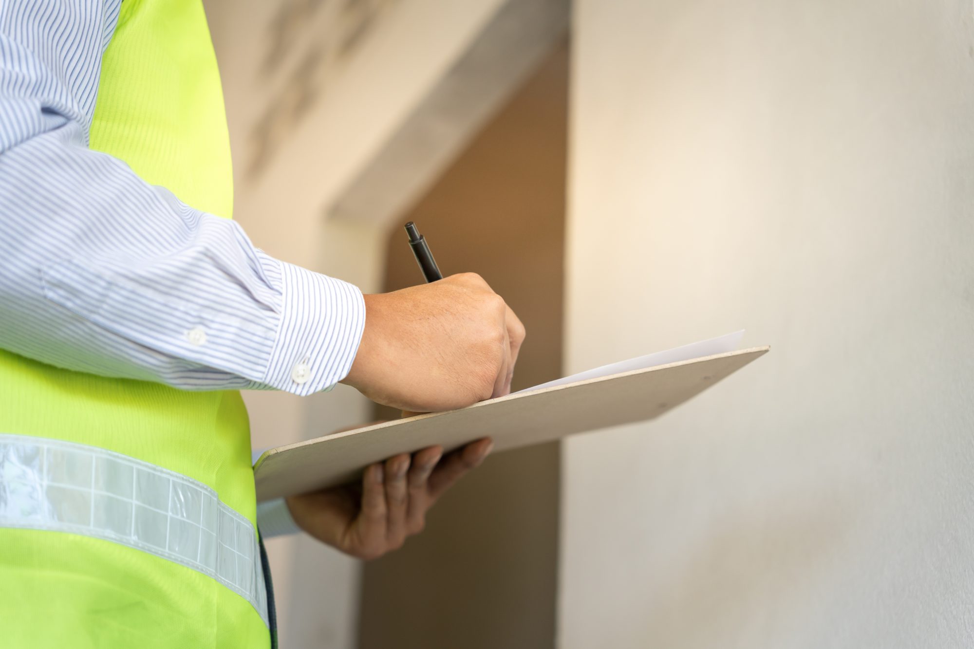 Surveyor recording findings on a clipboard during a RICS home survey